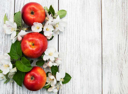 apples and apple tree blossoms on a wooden backgroundの写真素材