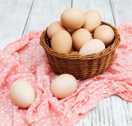 chicken eggs in basket on a old wooden tableの写真素材