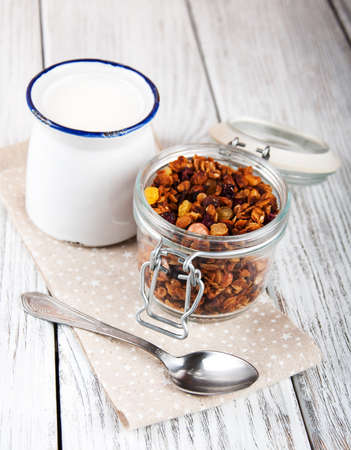 homemade granola in open glass jar and milk on a old wooden tableの写真素材