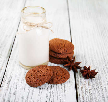 oatmeal cookies and bottle of milk on a old wooden tableの写真素材