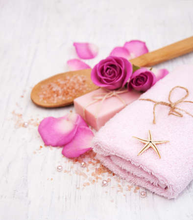 Bath towels, salt and soap with pink roses on a old wooden backgroundの写真素材