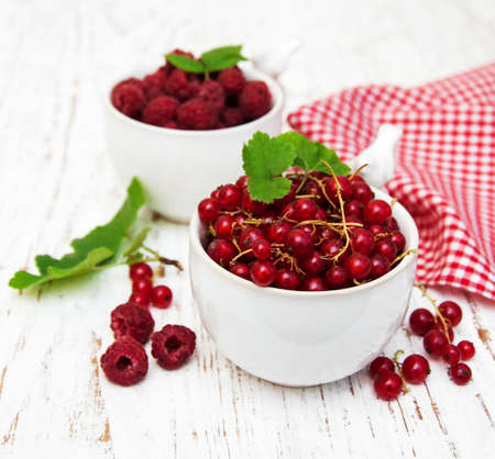 fresh red currant and raspberries on a old wooden tableの写真素材