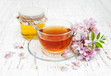 cup of tea and honey with acacia blossoms on a wooden backgroundの写真素材