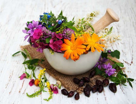 wild flower and herb leaf in mortar on a wooden backgroundの写真素材