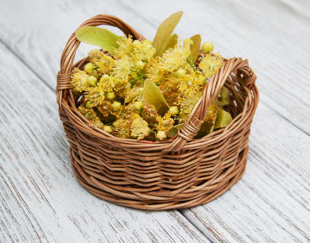 wicker basket with lime flowers on a old wooden backgroundの写真素材