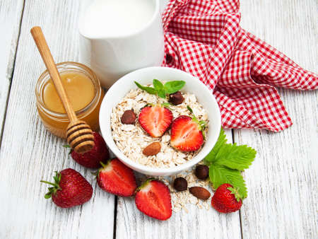 Muesli with strawberries, milk and honey on a old wooden tableの写真素材