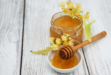 Jar with honey and linden flowers on a wooden backgroundの写真素材