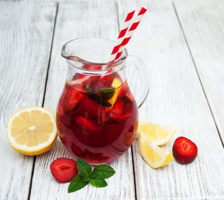 Glasses of lemonade with strawberries, lemon and mint on a old wooden tableの写真素材