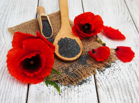 Poppy seeds and poppy flowers on a wooden backgroundの写真素材