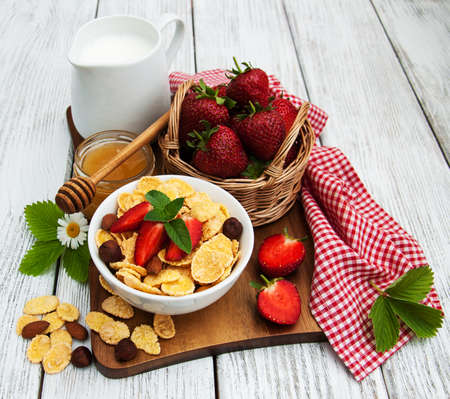 Muesli with strawberries, milk and honey on a old wooden tableの写真素材
