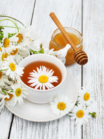 cup of herbal tea with chamomile flowers on a wooden tableの写真素材