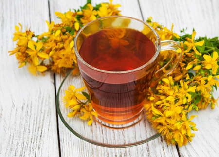 herbal tea in a glass cup and fresh flowers tutsan on the tableの写真素材