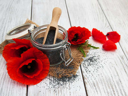Poppy seeds and poppy flowers on a wooden backgroundの写真素材