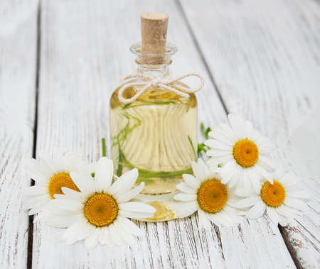 Massage oil and chamomile on a old wooden backgroundの写真素材