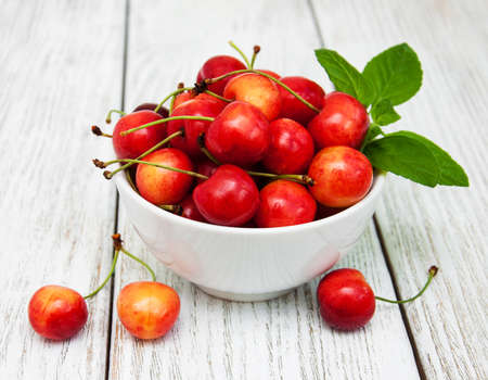 Bowl with sweet cherry merry on a old wooden tableの写真素材