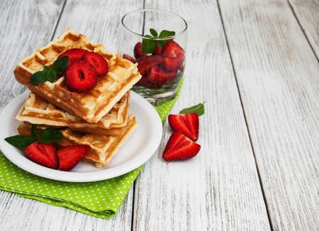 belgian waffles with strawberries and mint with milk on a wooden tableの写真素材