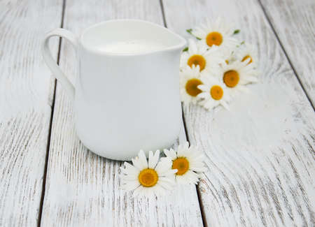 jug with milk  and chamomile flower on a wooden tableの写真素材