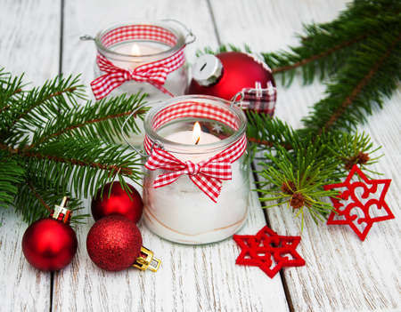 christmas decorations candles in glass jars with fir on a old wooden tableの写真素材