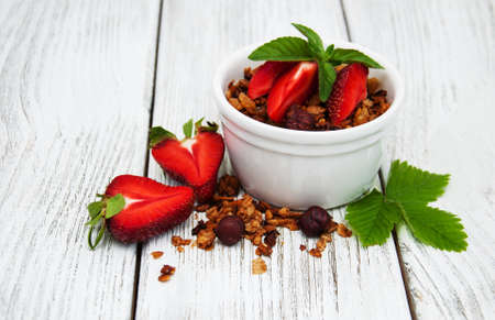 Homemade granola  with strawberries on a old wooden tableの写真素材