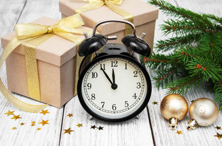 christmas clock on a  wooden background with fir tree and gift boxes