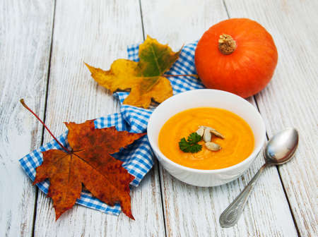 Pumpkin soup with fresh pumpkins on a old wooden tableの写真素材