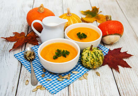 Pumpkin soup with fresh pumpkins on a old wooden tableの写真素材