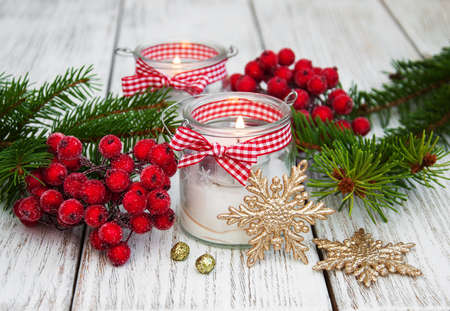 christmas decorations candles in glass jars with fir on a old wooden tableの写真素材