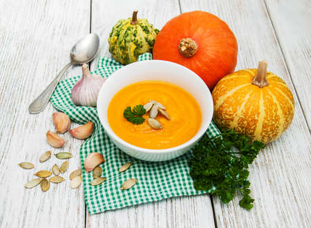 Pumpkin soup with fresh pumpkins on a old wooden tableの写真素材