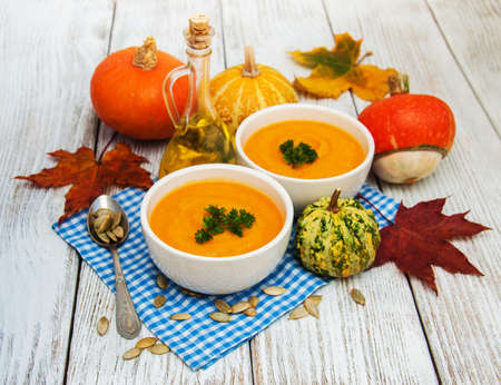 Pumpkin soup with fresh pumpkins on a old wooden tableの写真素材