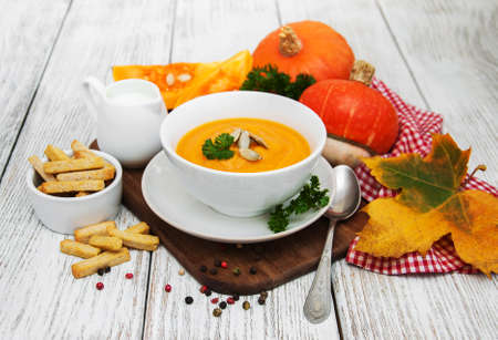 Pumpkin soup with fresh pumpkins on a old wooden tableの写真素材