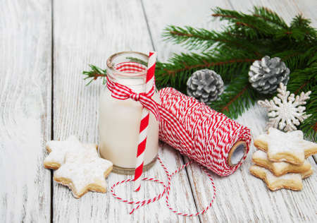 Christmas cookies and milk with decorations on a wooden tableの写真素材