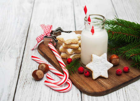 Christmas cookies and milk with decorations on a wooden tableの写真素材