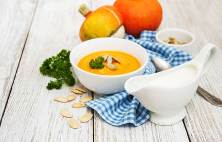 Pumpkin soup with fresh pumpkins on a old wooden tableの写真素材