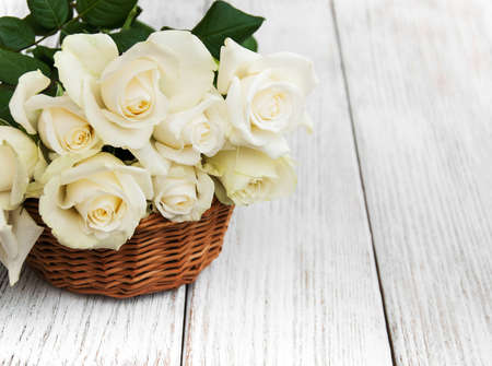 Basket with white roses on a old wooden tableの写真素材