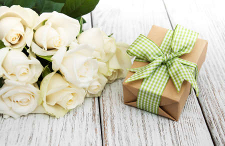 White roses and gift box on a old white wooden tableの写真素材