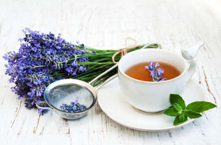 Cup of tea and lavender flowers on a old wooden backgroundの写真素材