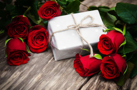 Red roses and gift box on a wooden tableの写真素材