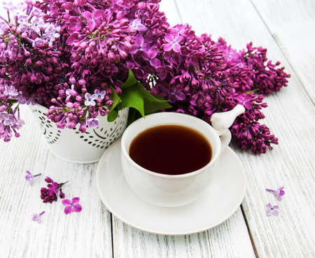 Cup of tea and lilac flowers on a wooden tableの写真素材