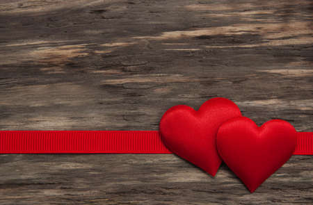 Fabric hearts and red ribbon on a wooden backgroundの写真素材