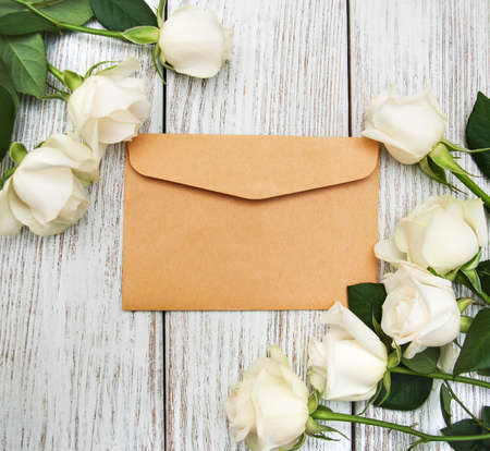 White roses with envelope on a old white wooden tableの写真素材