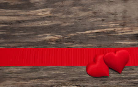 Fabric hearts and red ribbon on a wooden backgroundの写真素材