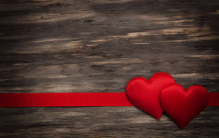 Fabric hearts and red ribbon on a wooden backgroundの写真素材