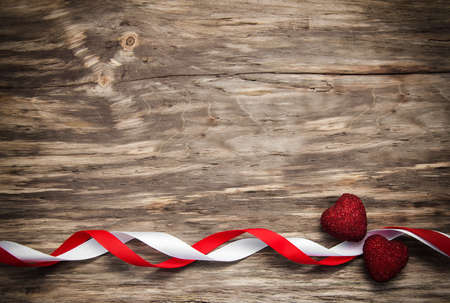 Hearts and red ribbon on a wooden backgroundの写真素材