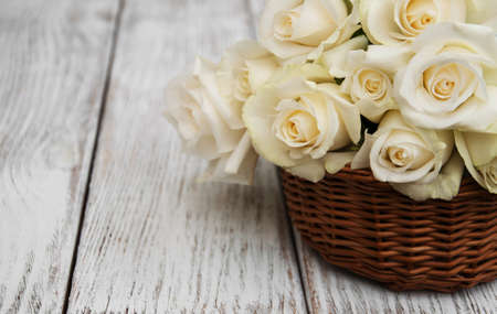 Basket with white roses on a old wooden tableの写真素材