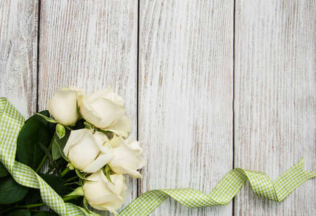 White roses with ribbon on a old white wooden tableの写真素材