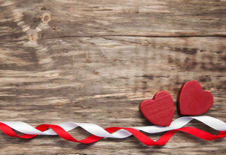 Hearts and red ribbon on a wooden backgroundの写真素材