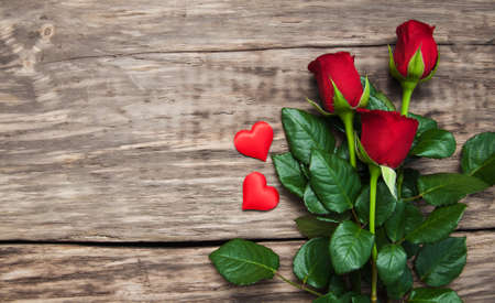 Red roses  with  hearts  on a old wooden tableの写真素材