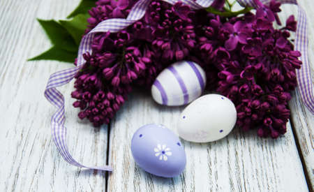 easter eggs and fresh lilac flowers on a old wooden background