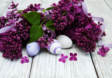 easter eggs and fresh lilac flowers on a old wooden backgroundの写真素材