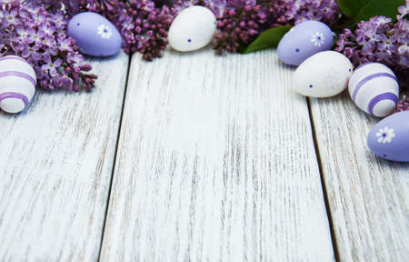 easter eggs and fresh lilac flowers on a old wooden backgroundの写真素材